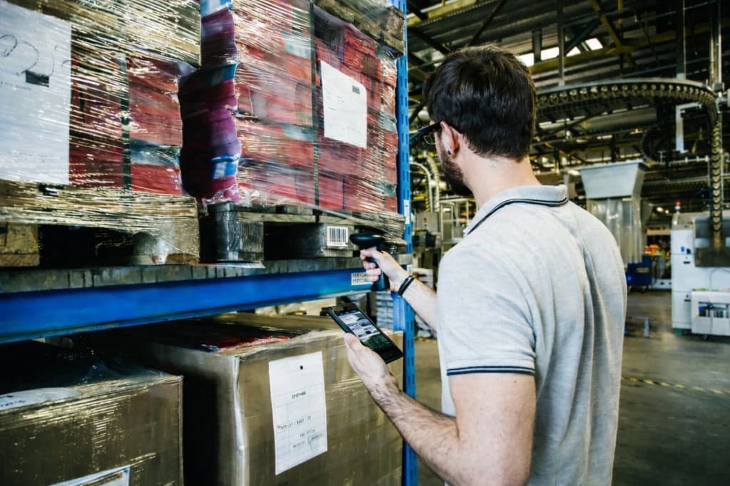 Worker scanning pallets to complete compliance reporting